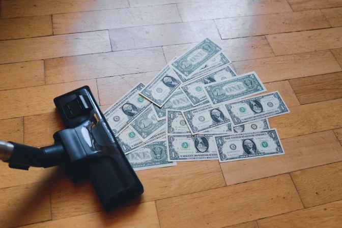 A pile of money sitting on top of a wooden floor.