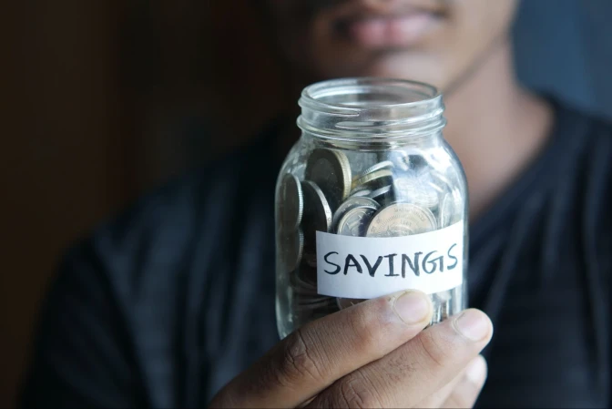 A man holding a jar with savings label