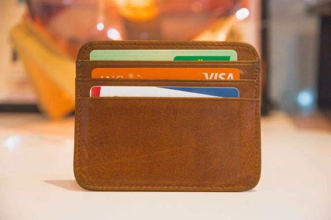 3 credit cards placed inside a brown leather card holder in each of the three card slots