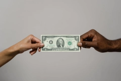 two hands holding a two-dollar bill in front of a white background
