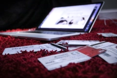 a messy pile of debit cards and a laptop placed on a red wool carpet