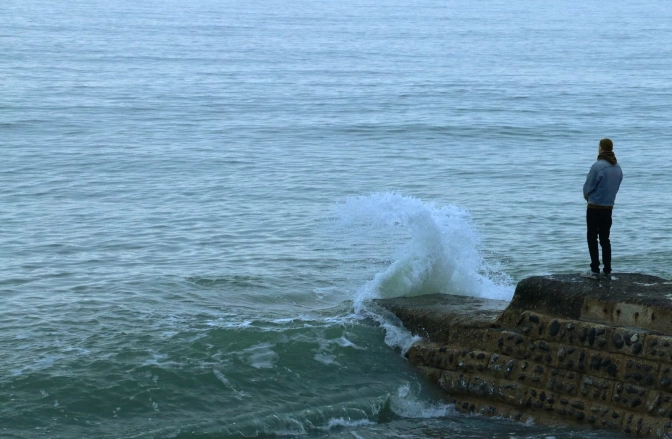 Person standing on the rocks near the ocean waves