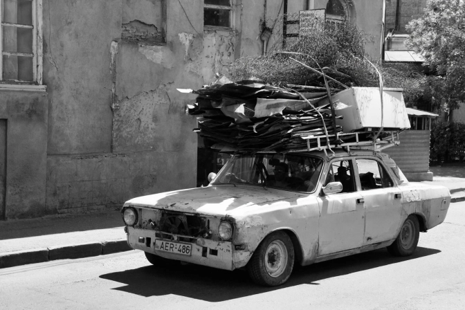 A Person Driving a Shabby Car Carrying Metal Scraps