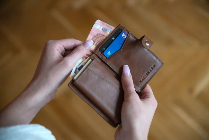 Person holding brown leather wallet with credit cards&nbsp;
