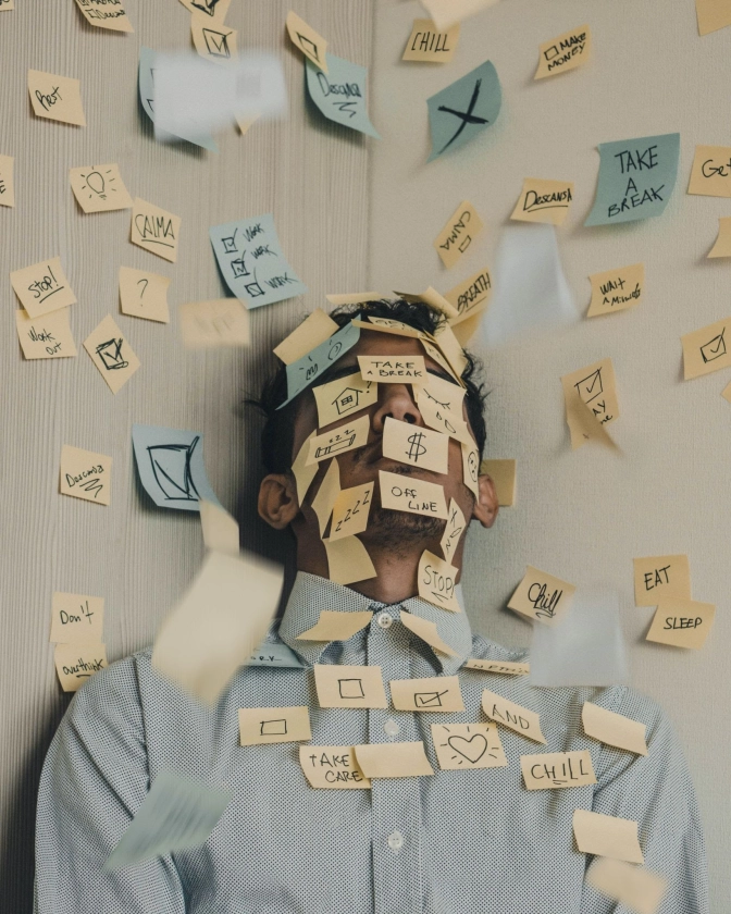 &nbsp; Young man covered in sticky notes displaying work overload&nbsp;