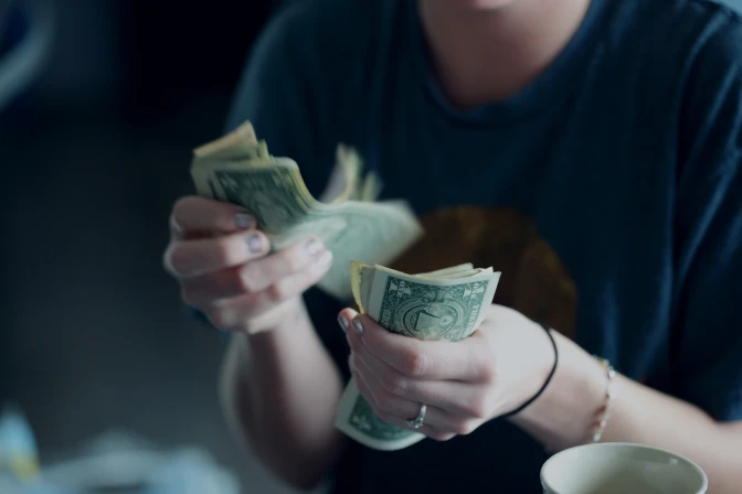 Focus photography of a person holding dollar banknotes