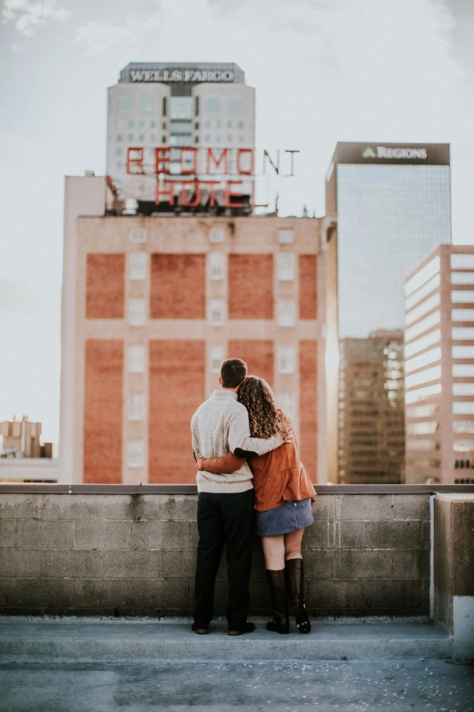 A couple hugging side by side on a rooftop&nbsp;