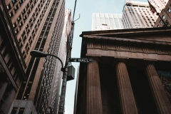 a streetlight with Wall Street signage in between buildings