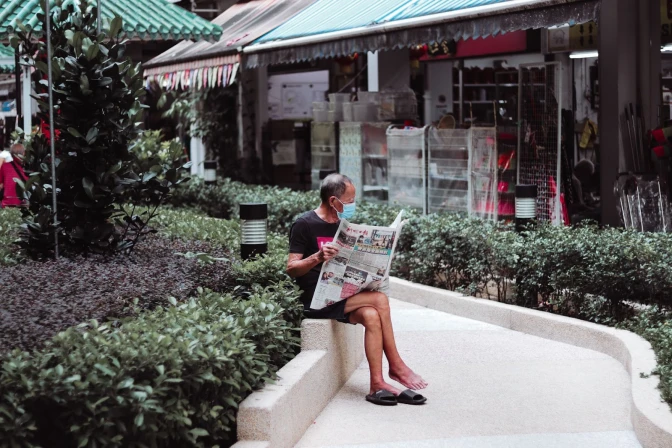 A man sitting on a bench reading a newspaper